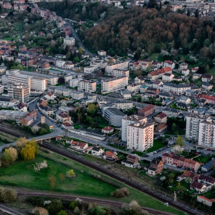 Vue aérienne d’une ville avec voies ferrées, immeubles et collines boisées